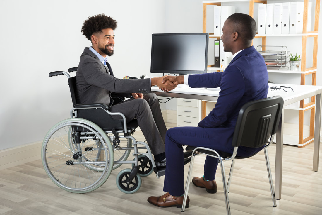 Smiling wheelchair user shaking hands in an office setting